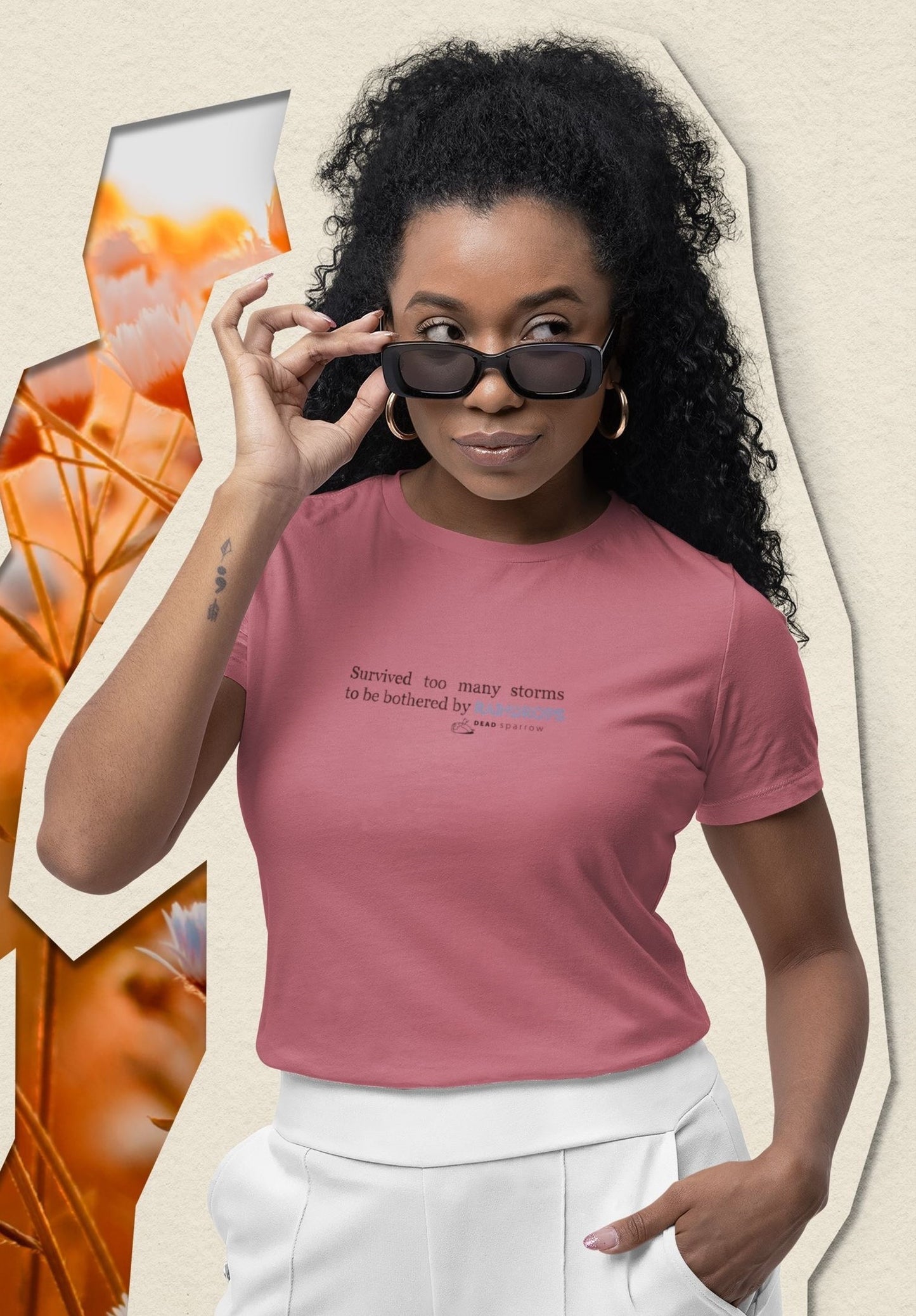 Image of a woman wearing a white DEADsparrow t-shirt. The product name of this t-shirt is Survivor.. In the centre of the t-shirt is a quote that reads "Survived too many storms to be bothered by raindrops". DEADsparrow.store.