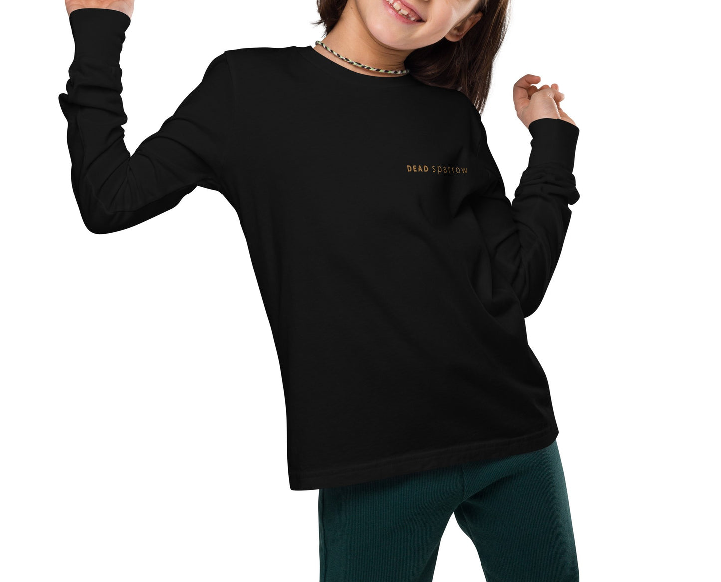 Image of a girl in a long-sleeved t-shirt with the DEADsparrow logo printed on the left side. The colour of the long-sleeved t-shirt is black with a gold print. Product name Skilled.