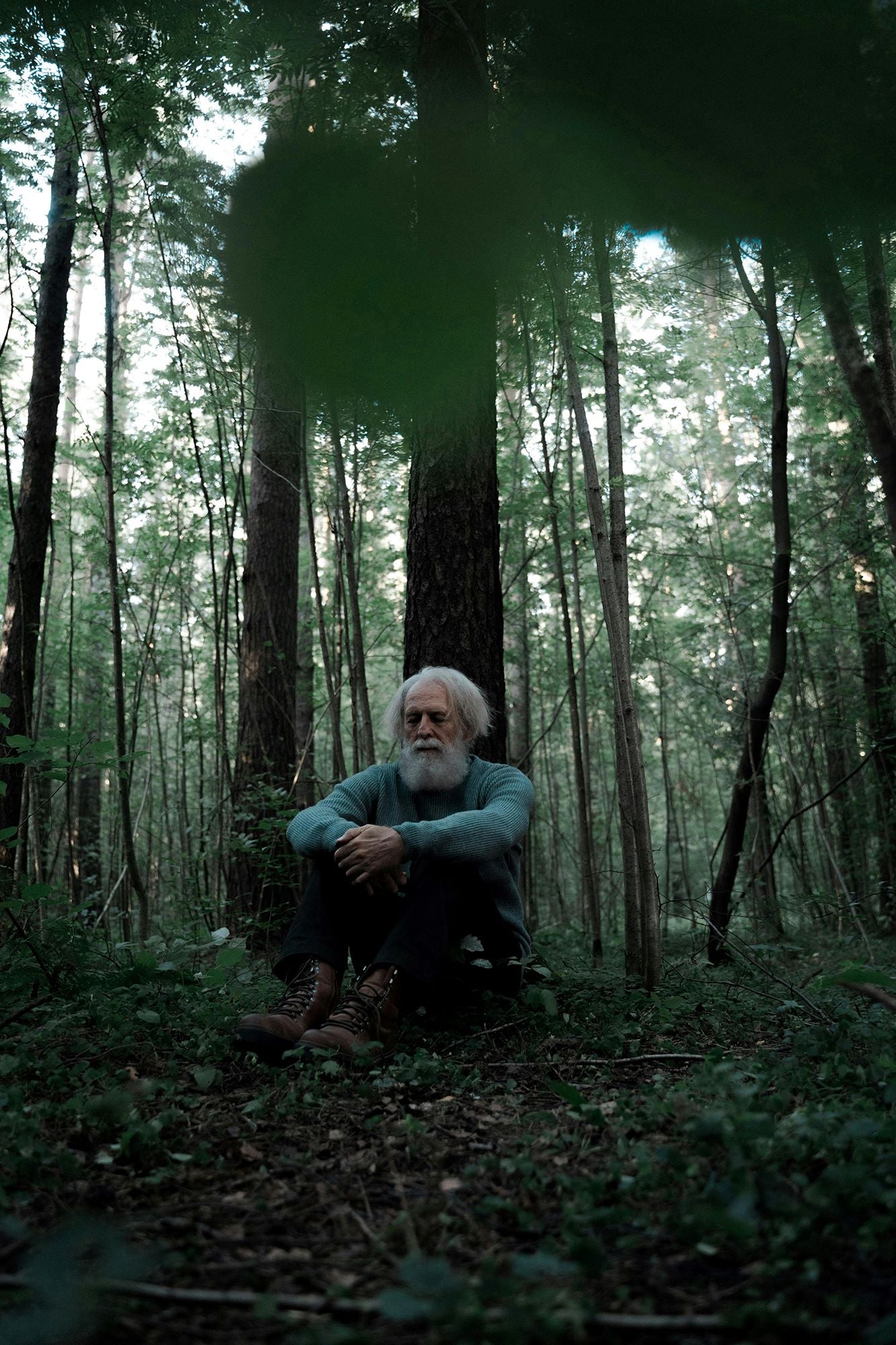 Image of man in the forest, sitting on the ground and meditating.