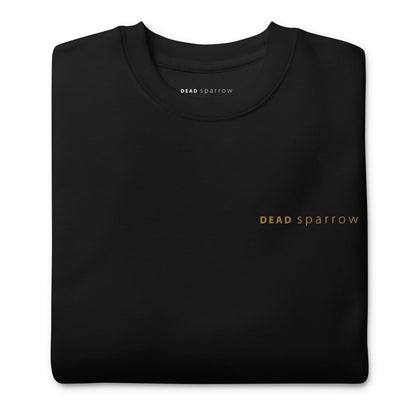 Close-up of a folded organic sweatshirt in the colour black. The text "Deadsparrow" embroidered on the left side of the sweatshirt in gold thread. Product name Enough.