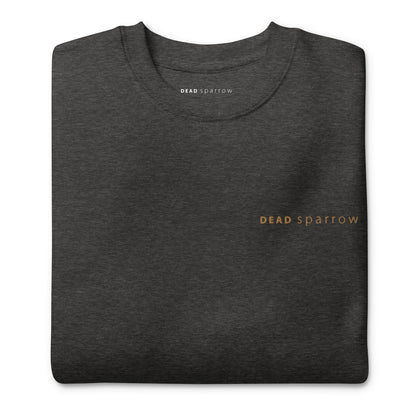 Close-up of a folded organic sweatshirt in the colour charcoal heather. The text "Deadsparrow" embroidered on the left side of the sweatshirt in gold thread. Product name Enough.