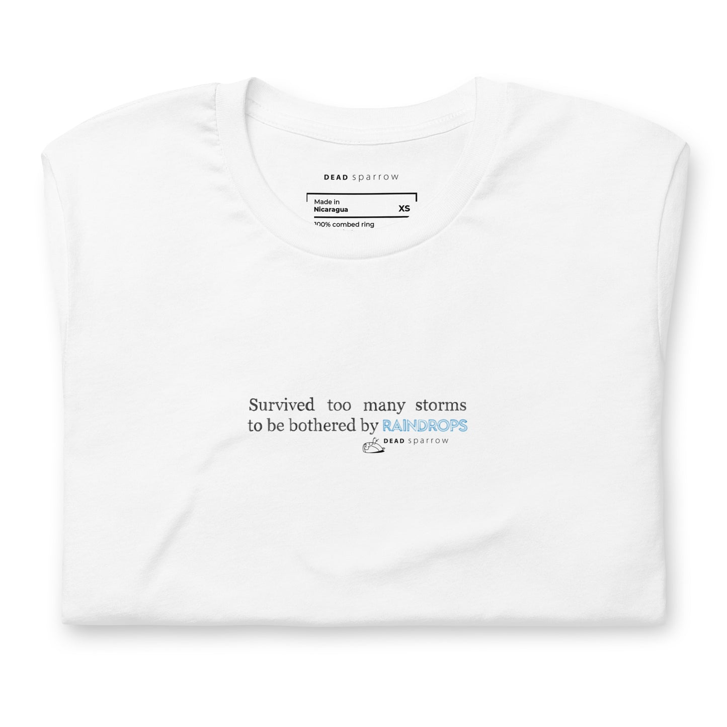 Image of a Survivor t-shirt for women. In the picture, the t-shirt is folded and has the colour white. The t-shirt has the quote "Survived too many storms to be bothered by raindrops". DEADsparrow.store.