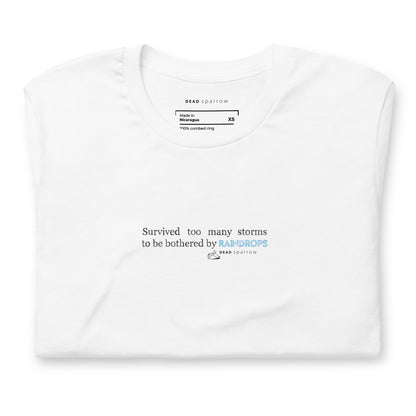 Image of a Survivor t-shirt for women. In the picture, the t-shirt is folded and has the colour white. The t-shirt has the quote "Survived too many storms to be bothered by raindrops". DEADsparrow.store.