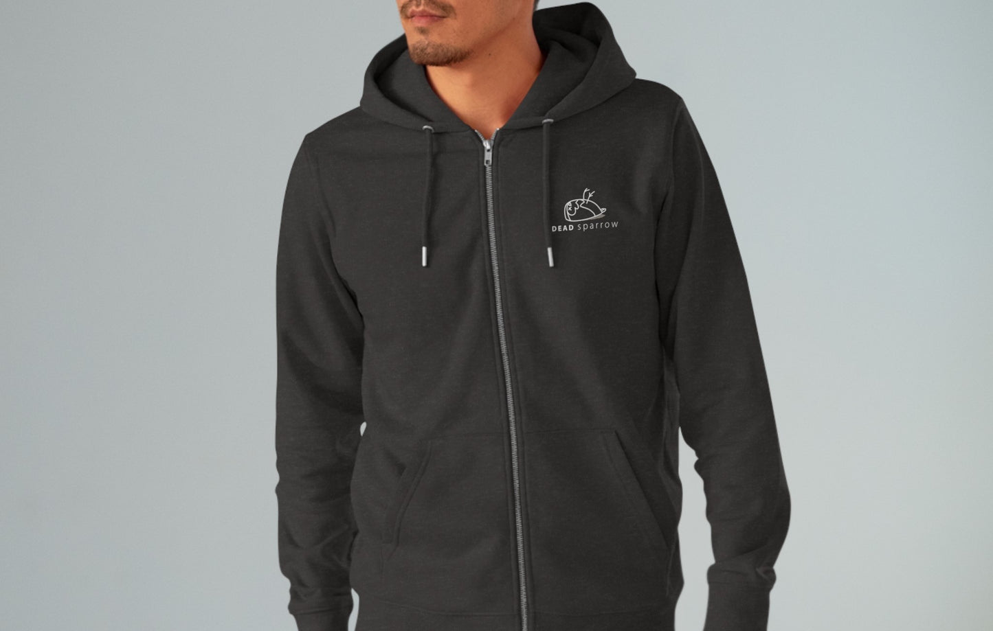 Close-up of a man wearing a dark grey zip-up hoodie, product name Impeccable. The hoodie has a print on the left side, 'DEAD sparrow' (logo).