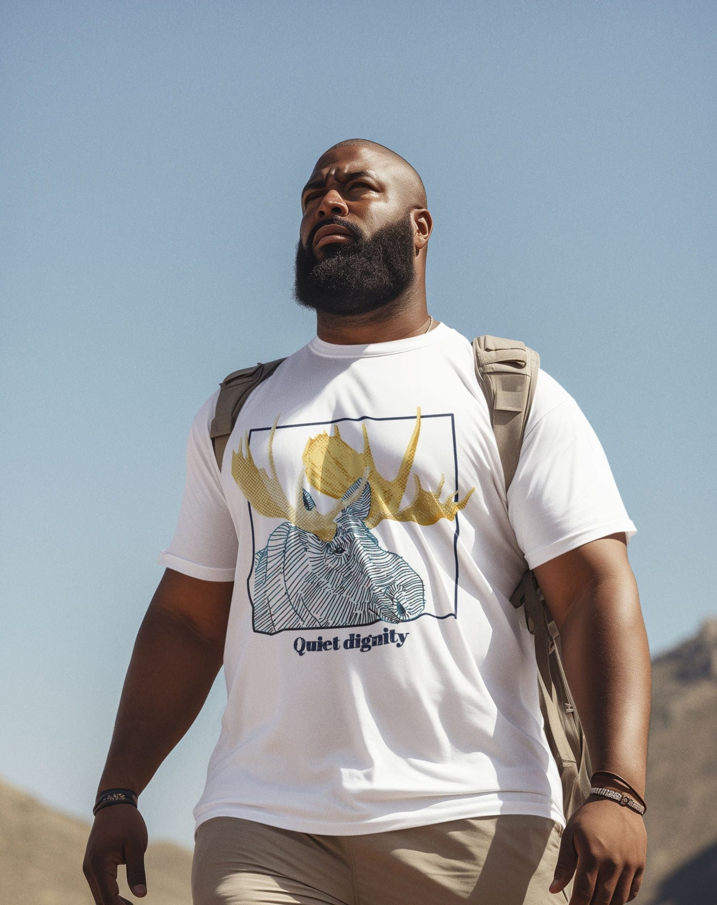 Image of a man wearing a white T-shirt with a moose print. Below the print is the phrase "Quiet Dignity".