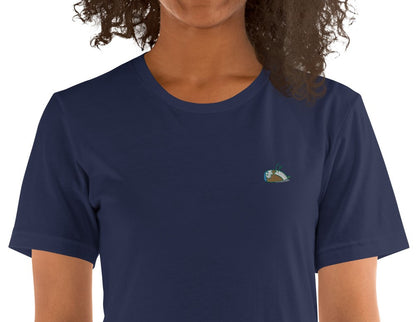 Close-up of a woman wearing a navy t-shirt, product name Wise. T-shirt with a sparrow embroidered on the left side/chest.